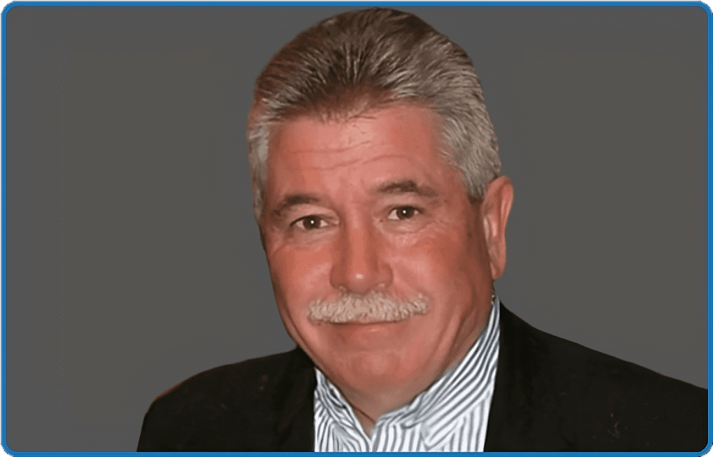 A man with grey hair and mustache wearing a suit.